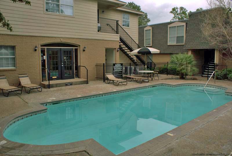 A small swimming pool surrounded by apartment rental units.
